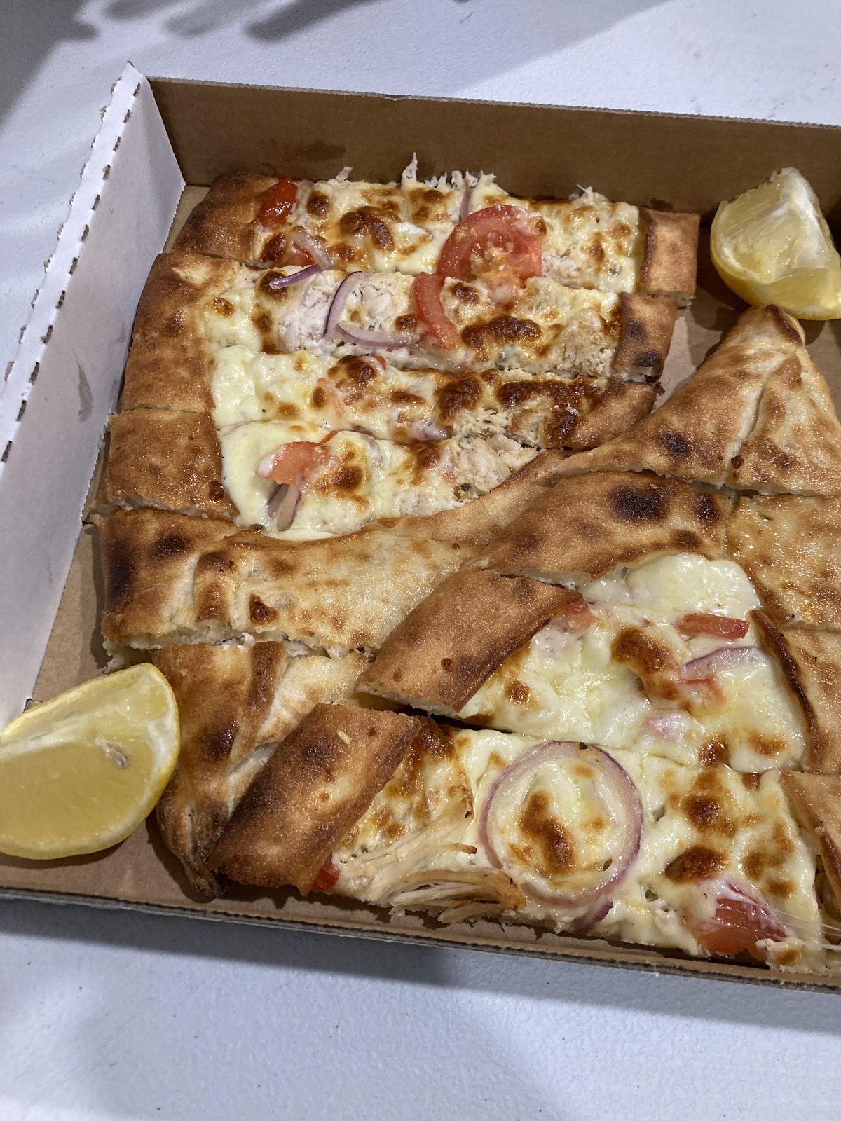 Turkish pide cut into strips in a takeaway box with lemon
