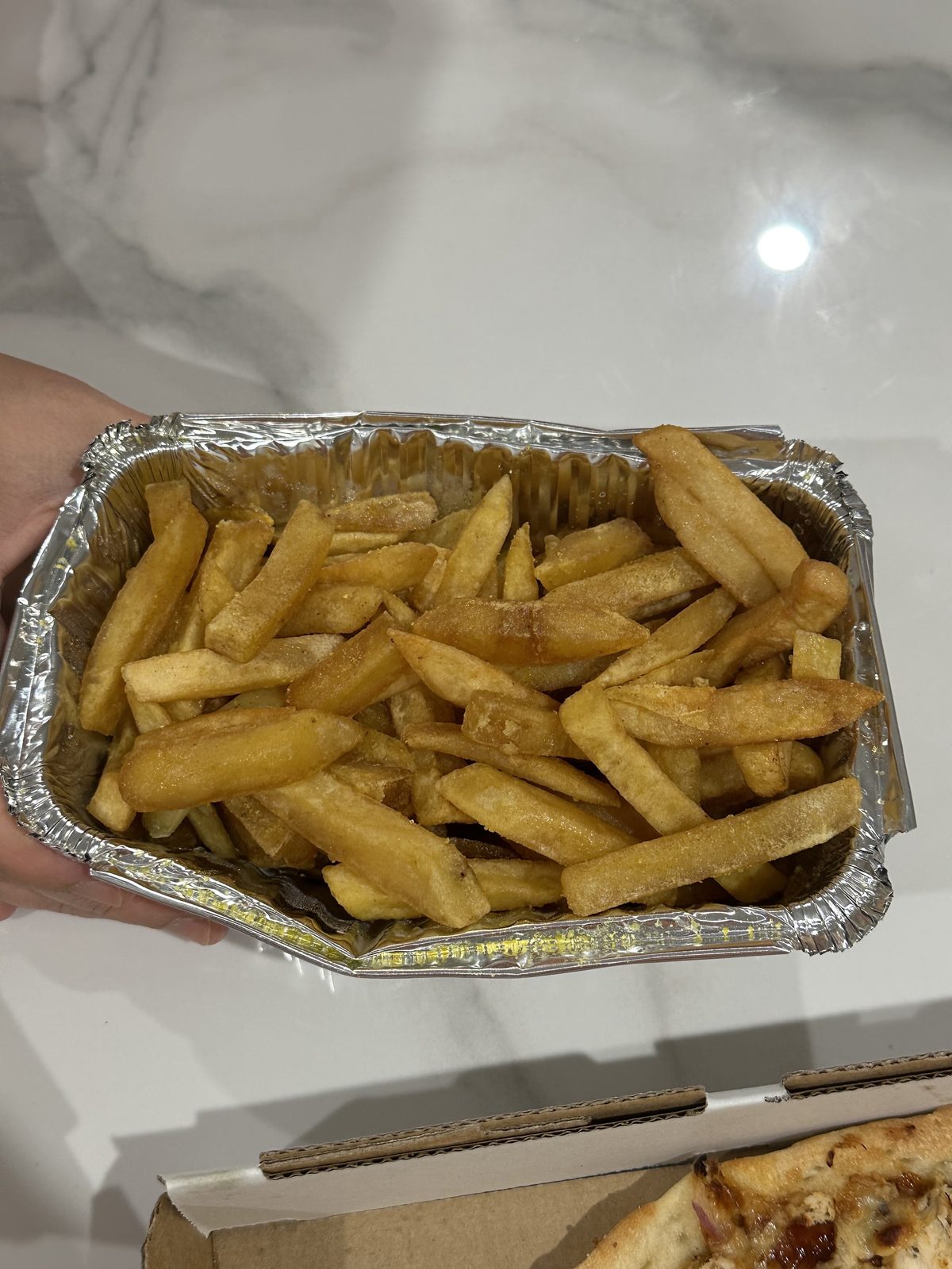 Seasoned chips in a foil takeaway tray